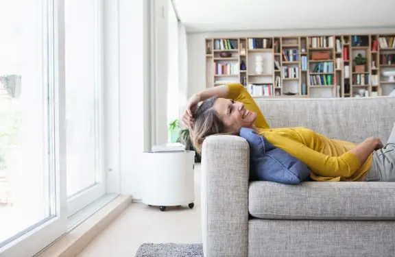 Frau liegt lächelnd auf dem Sofa