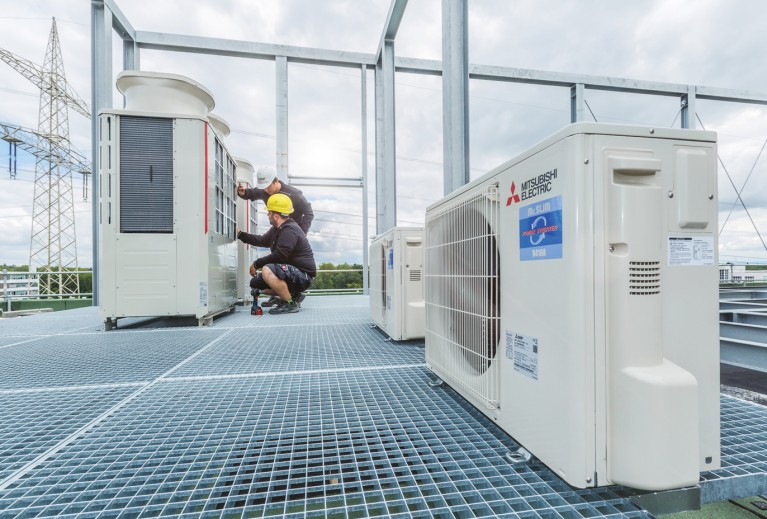 Männer auf dem Dach arbeiten an einem City Multi Hybrid VRF-Außengerät