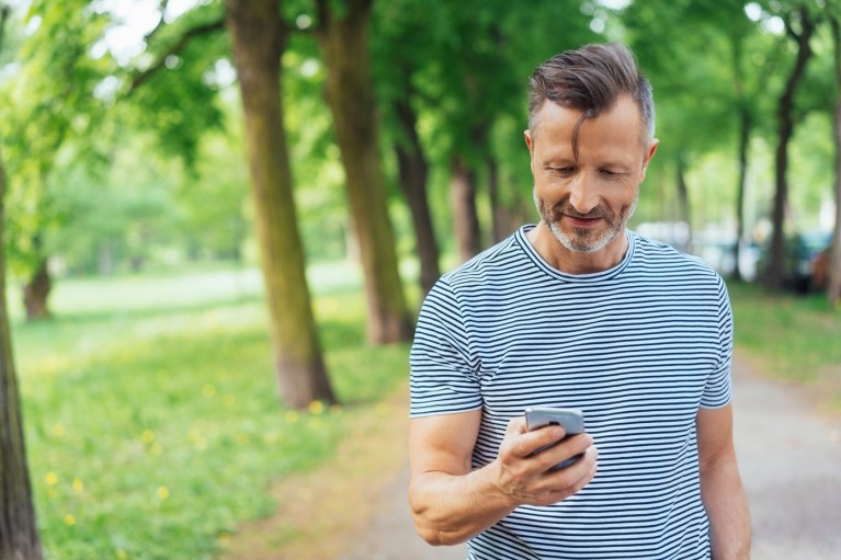 Thomas Miles im Park mit einem Handy in der Hand