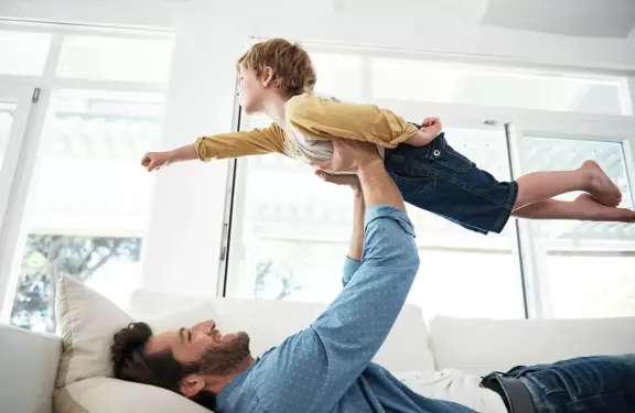 Zoon doet een vliegtuig na terwijl vader hem omhoog tilt met twee handen - hybride warmtepomp