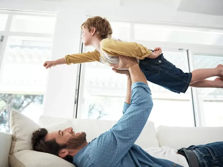 Le père soulève le bébé pour qu'il vole