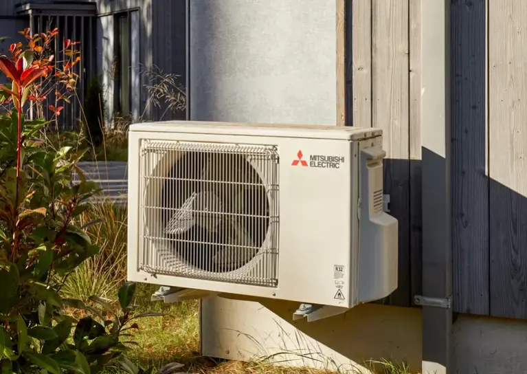 Witte buitenunit van Mitsubishi Electric hangt op bij een cottage van Centerparcks Terhils 