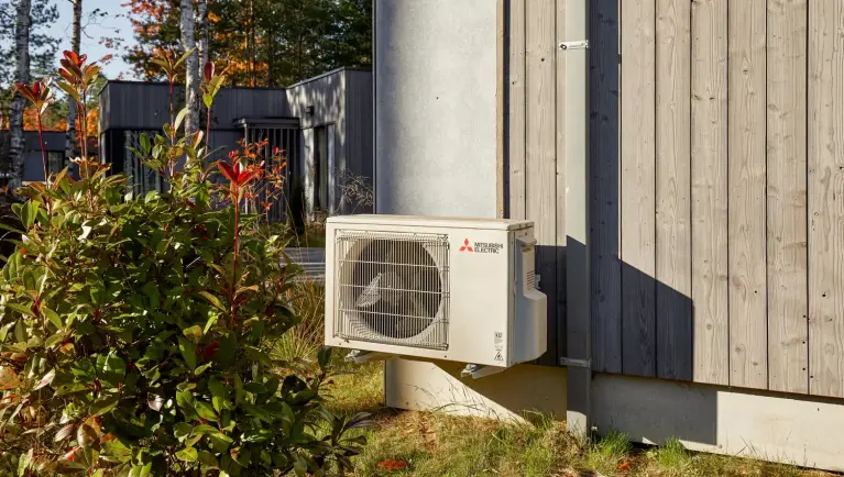 Witte buitenunit van Mitsubishi Electric hangt op bij een cottage van Centerparcs Terhills