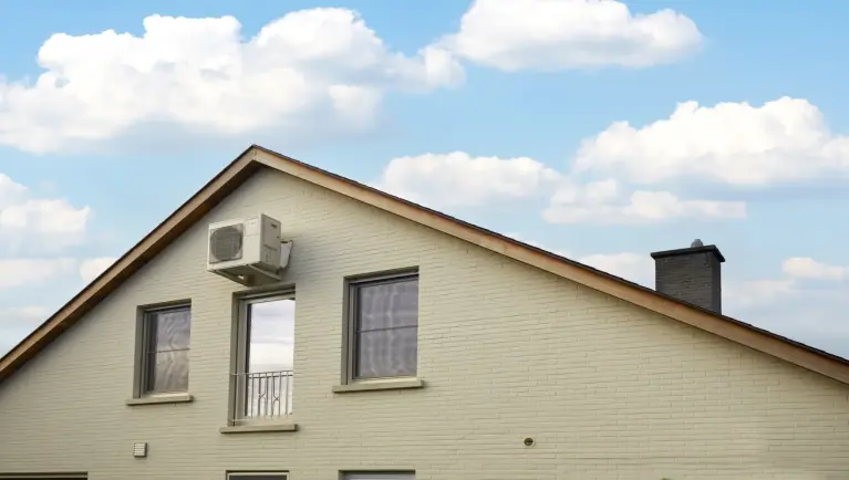 Witte buitenunit hangt op aan de buitenkant van het huis