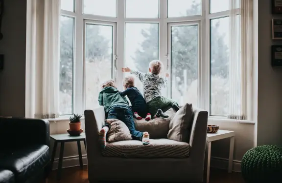 3 enfants regardant le froid extérieur depuis le canapé