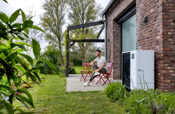 Man zit op terras te genieten naast zijn warmtepomp